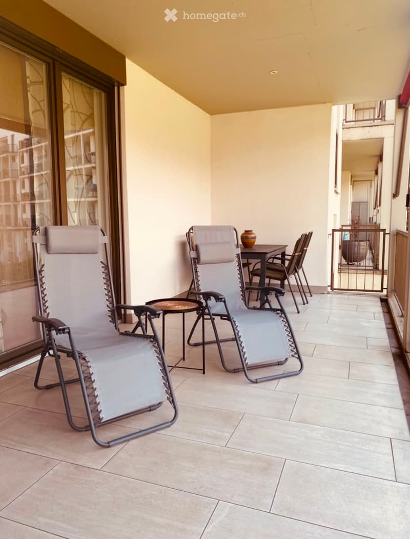 Balcony with tiled floor, two lounge chairs, small table, and dining set with chairs.