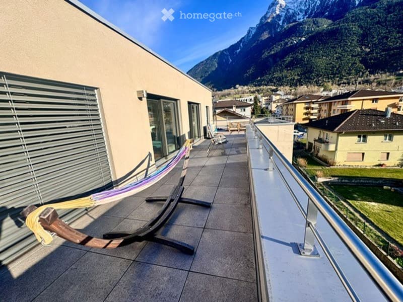 Balcony with a scenic mountain view, featuring a hammock and a few chairs.
