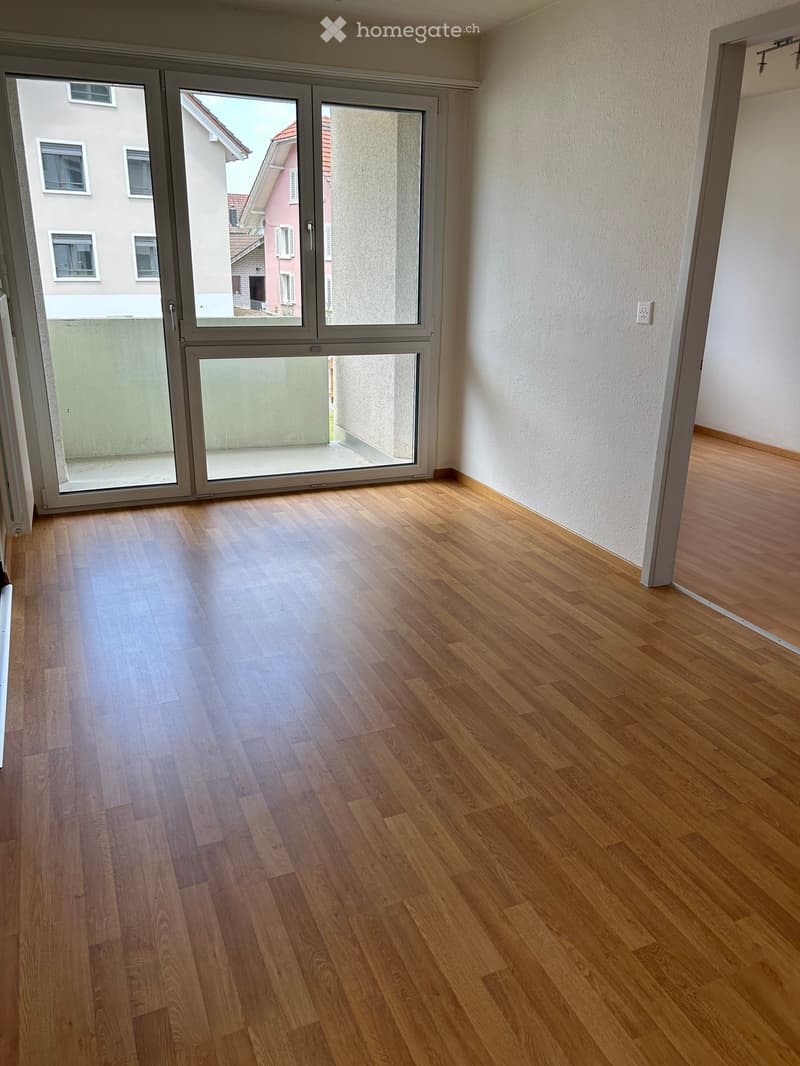 Empty room with wooden flooring and large sliding glass doors leading to a balcony or outdoor area.