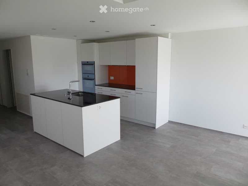 Modern kitchen with white cabinets, black countertop, stainless steel sink, and built-in oven. The space features a central island and ample storage.