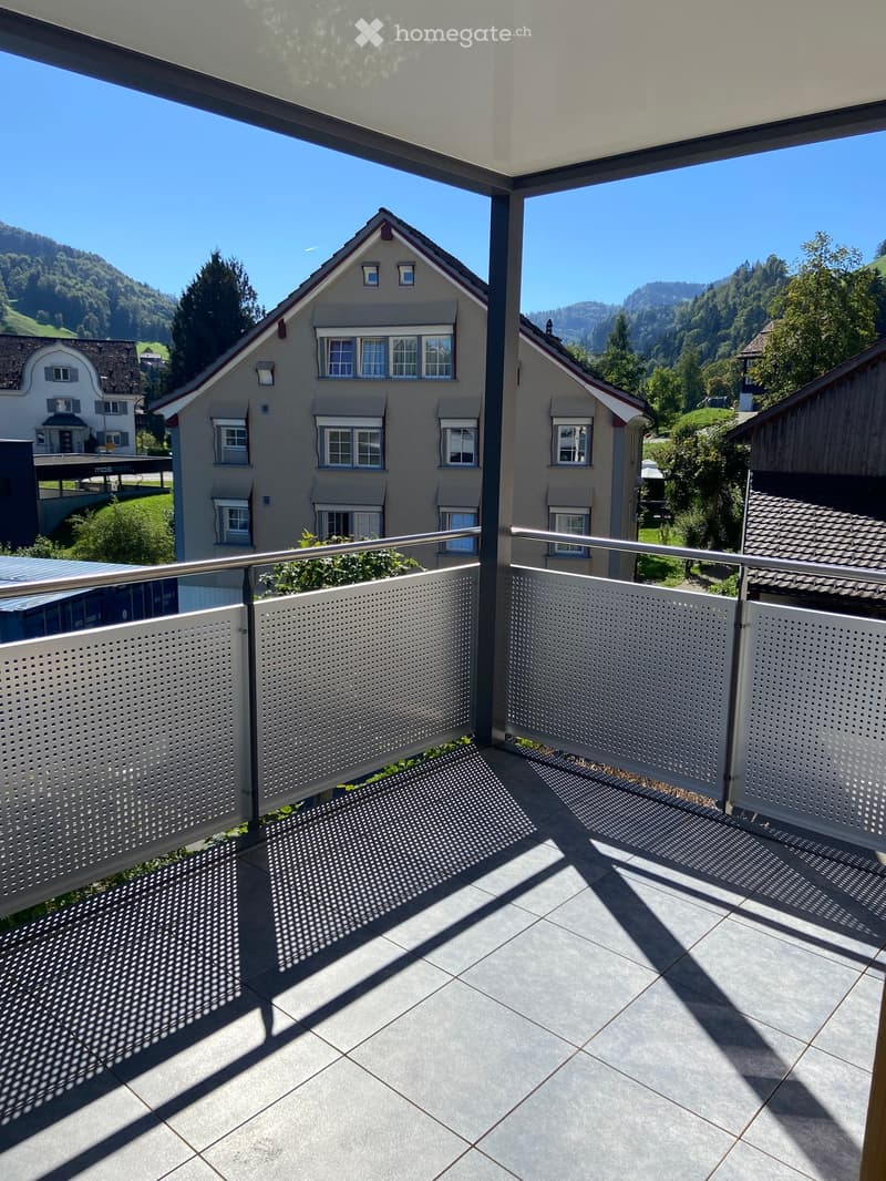 Balcony with tiled floor, metal railing, and a view of a residential house and surrounding greenery.