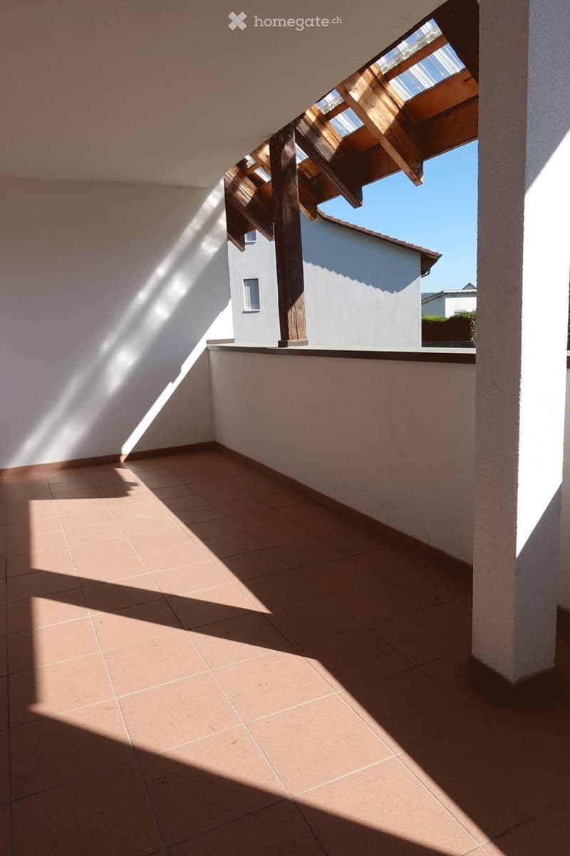 Balcony with tiled floor, wooden roof structure, and view of neighboring building.