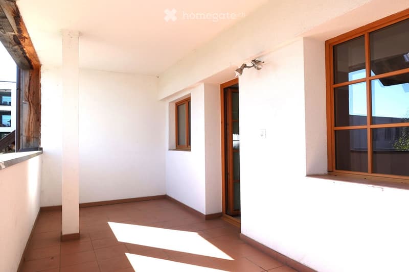 Empty room with white walls, tiled floor, and wooden-framed windows. No furniture or equipment present.