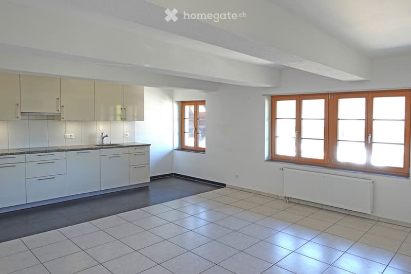 Modern kitchen with white cabinets, a sink, and large windows. The floor is tiled, and there is a radiator under one of the windows.