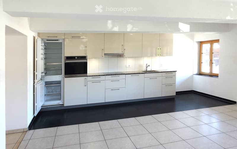 Modern kitchen with white cabinets, stainless steel appliances, black tiled floor, and a window with wooden frame.
