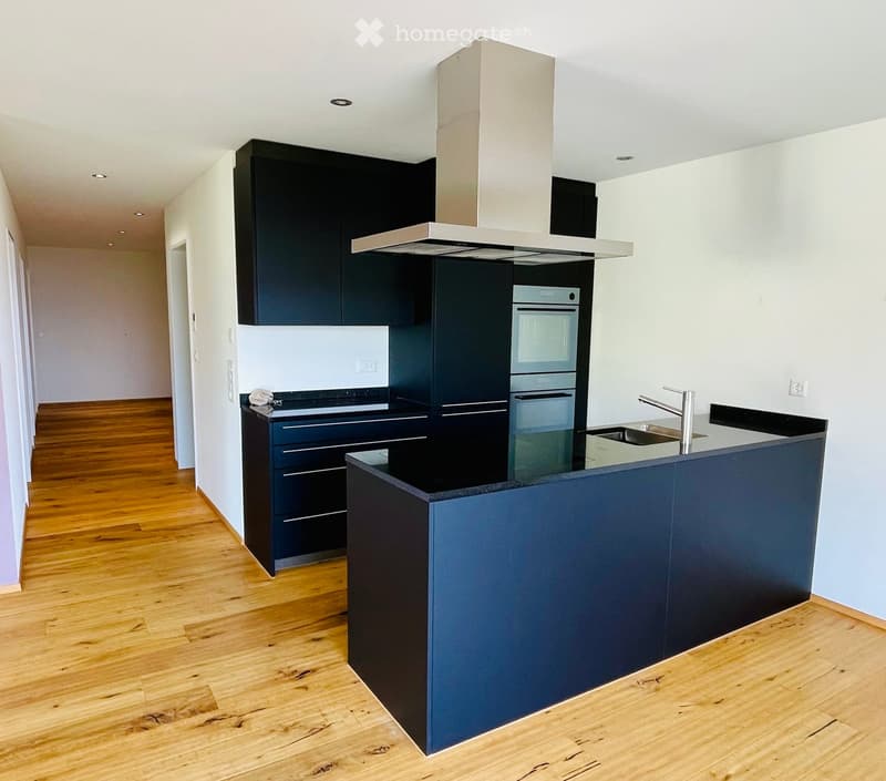 Modern kitchen with dark blue cabinets, stainless steel appliances, and a central island with a sink and faucet.