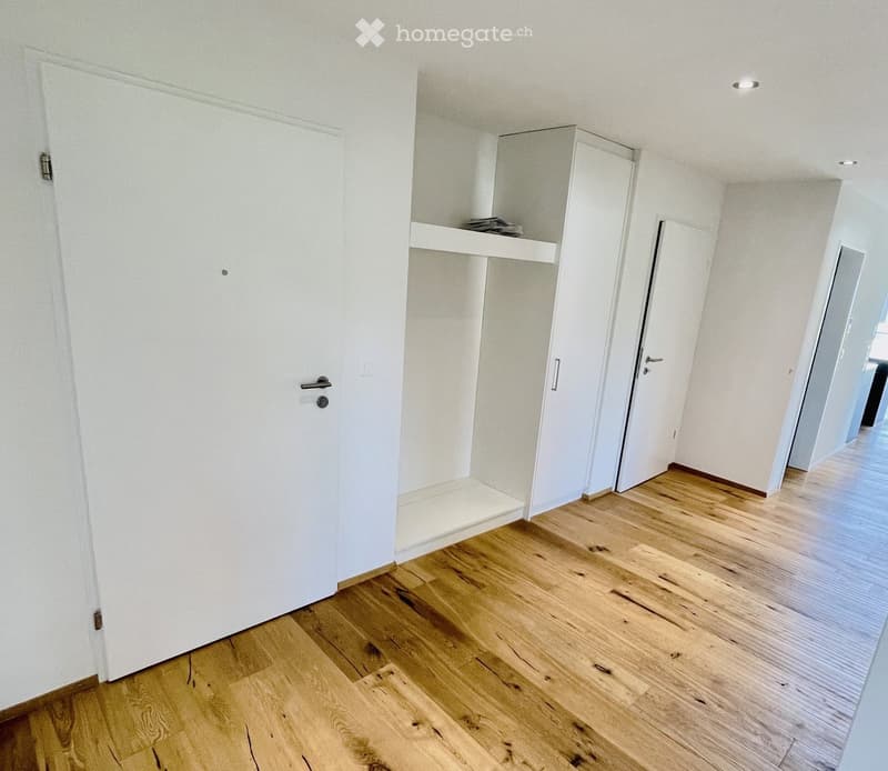 Empty room with wooden flooring, white walls, and built-in shelving unit. No furniture or personal items present.