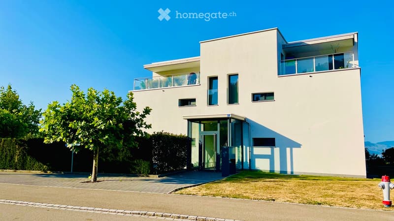 Modern two-story house with white exterior, large windows, and balconies on both levels.