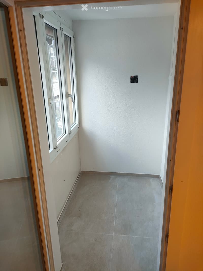 Empty room with windows, tiled floor, white walls