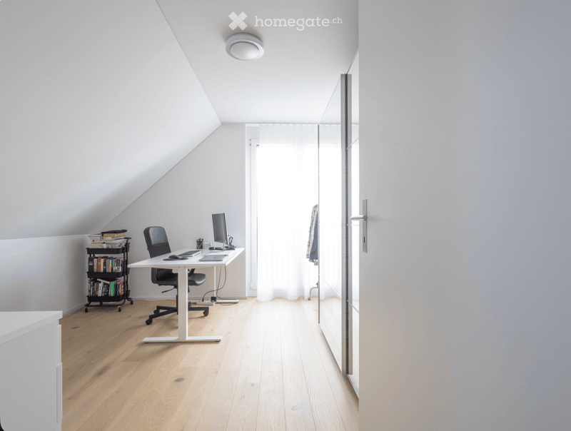 Bright, minimalist attic office with wooden flooring, white walls, and a skylight. Features a modern desk, ergonomic chair, laptop, bookshelf, and a large window with sheer curtains.
