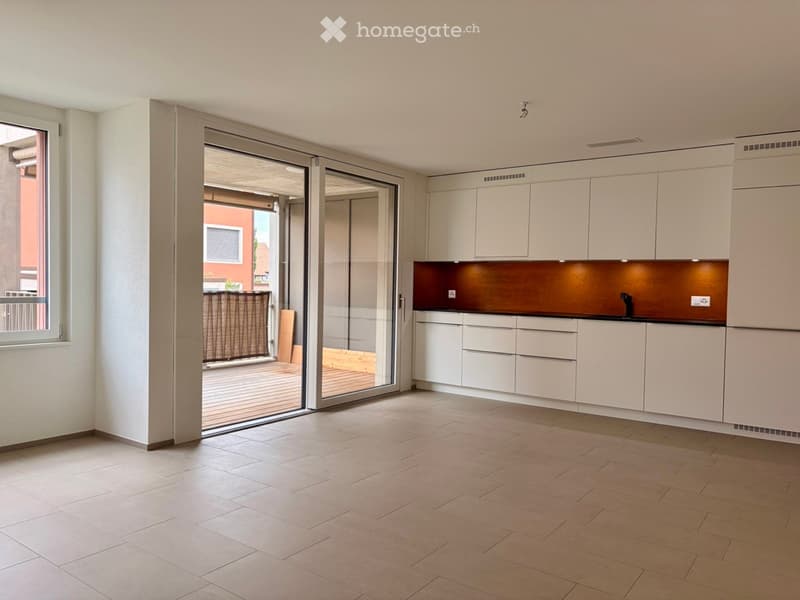 Modern kitchen with white cabinets, a dark countertop, and a large sliding glass door leading to a balcony.
