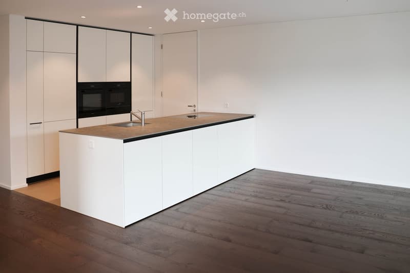 Modern kitchen with white cabinets, a central island, and a built-in oven. The island features a countertop and a sink with a modern faucet.