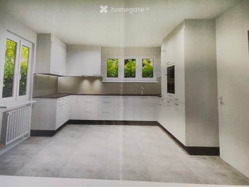 Modern, unfurnished kitchen with white cabinets, stainless steel appliances, and large windows letting in natural light. The space features a clean, minimalist design with a neutral color palette and a tiled floor.