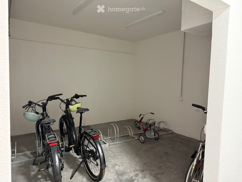 Garage with several bicycles and a bicycle rack, white walls, and concrete floor.