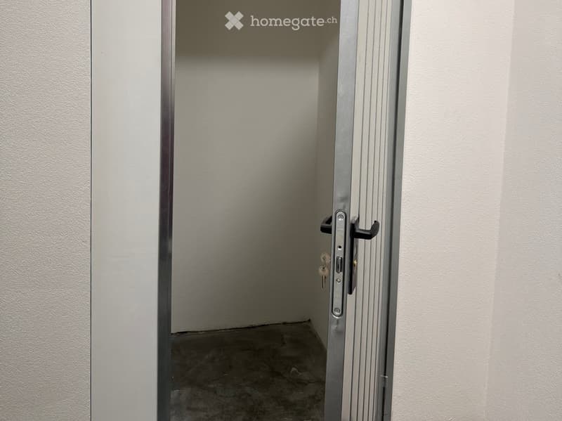 Empty room with a metal door and concrete floor, no furniture or equipment.