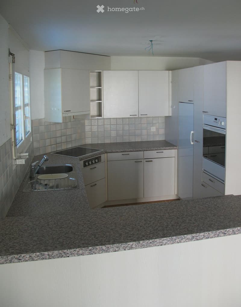 Modern kitchen with white cabinets, granite countertops, stainless steel sink, and built-in appliances including an oven and stove.