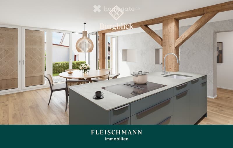 Modern kitchen with a central island, induction cooktop, sink, and pendant light. Dining area with a round table and chairs, flower vase, and outdoor view through large windows.