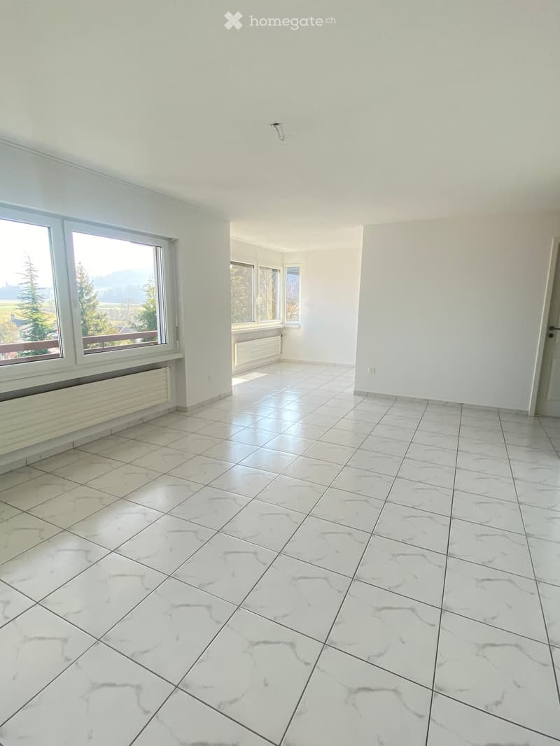Empty room with white tiled floor and large windows offering a scenic view. No furniture or equipment present.