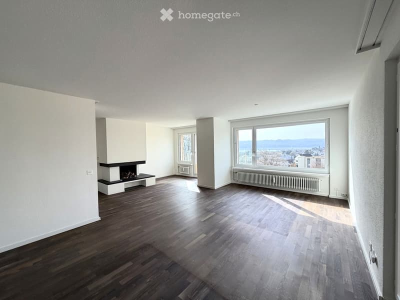 Empty room with hardwood floors, white walls, fireplace, window, radiator, and city view