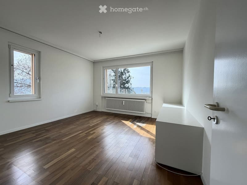 empty room with wooden floor, white walls, large windows, white radiator
