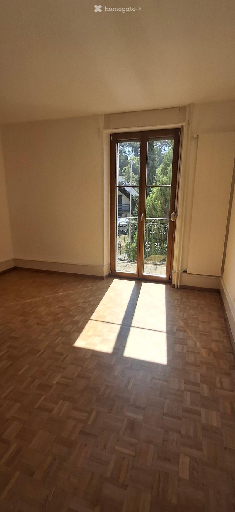 Empty room with wooden flooring and large sliding glass doors leading to a balcony or outdoor area.
