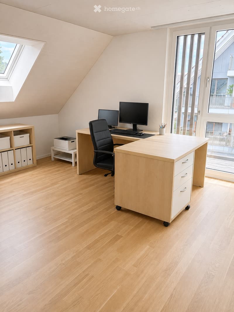Bright, modern office space with light wooden flooring, large windows, and a skylight. Features a desk with a computer setup, a comfortable office chair, and a storage unit with drawers.
