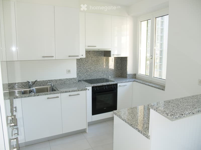Modern kitchen with white cabinets, granite countertops, and stainless steel sink and oven.