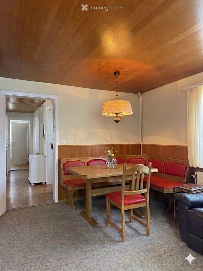 Dining area with wooden table, chairs, and a bench, wooden ceiling, white walls, a lamp, and a small white cabinet