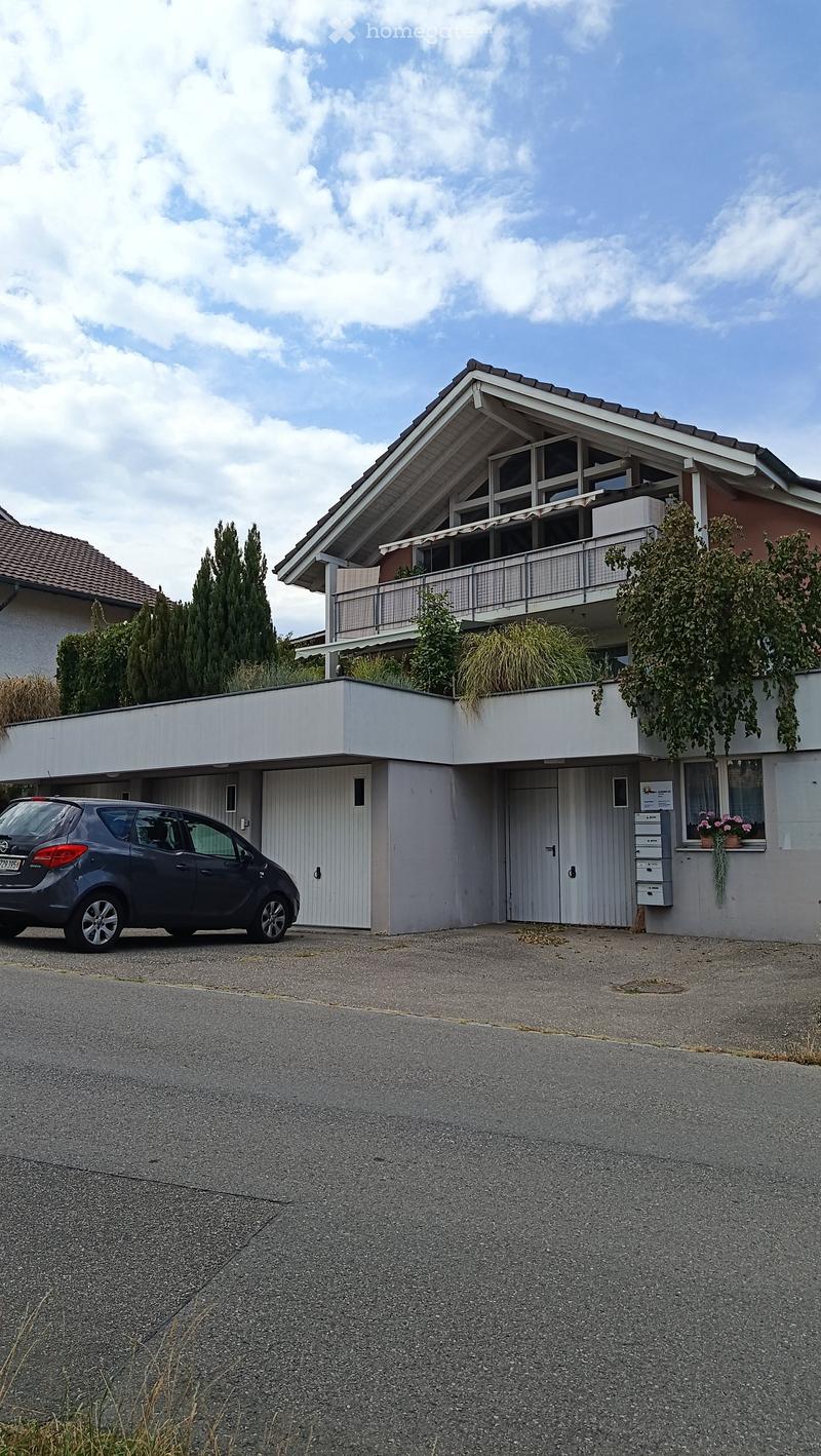 Two-story house with a garage, balcony, and parked car in front.