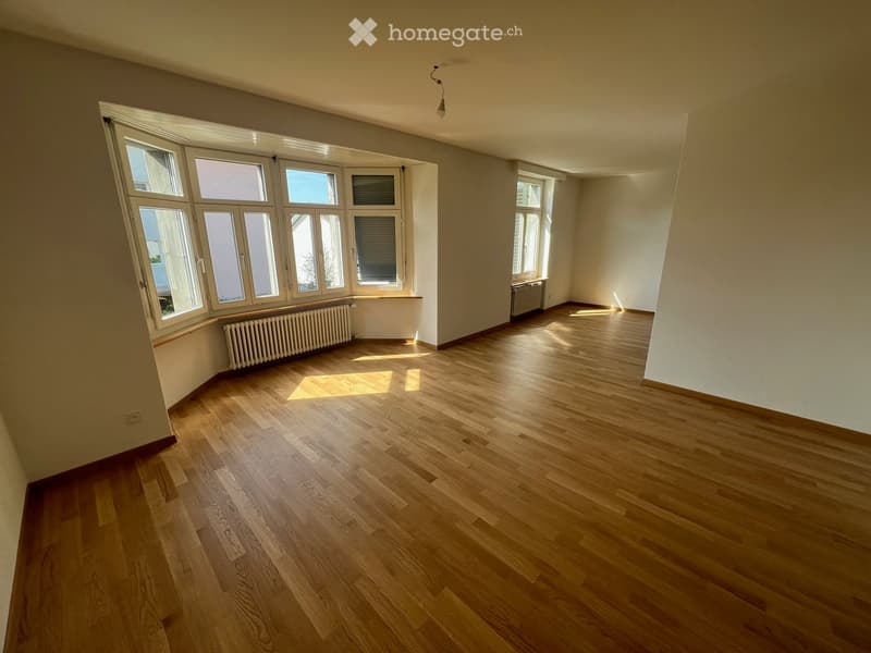 Empty room with hardwood floors, large windows, and radiators.