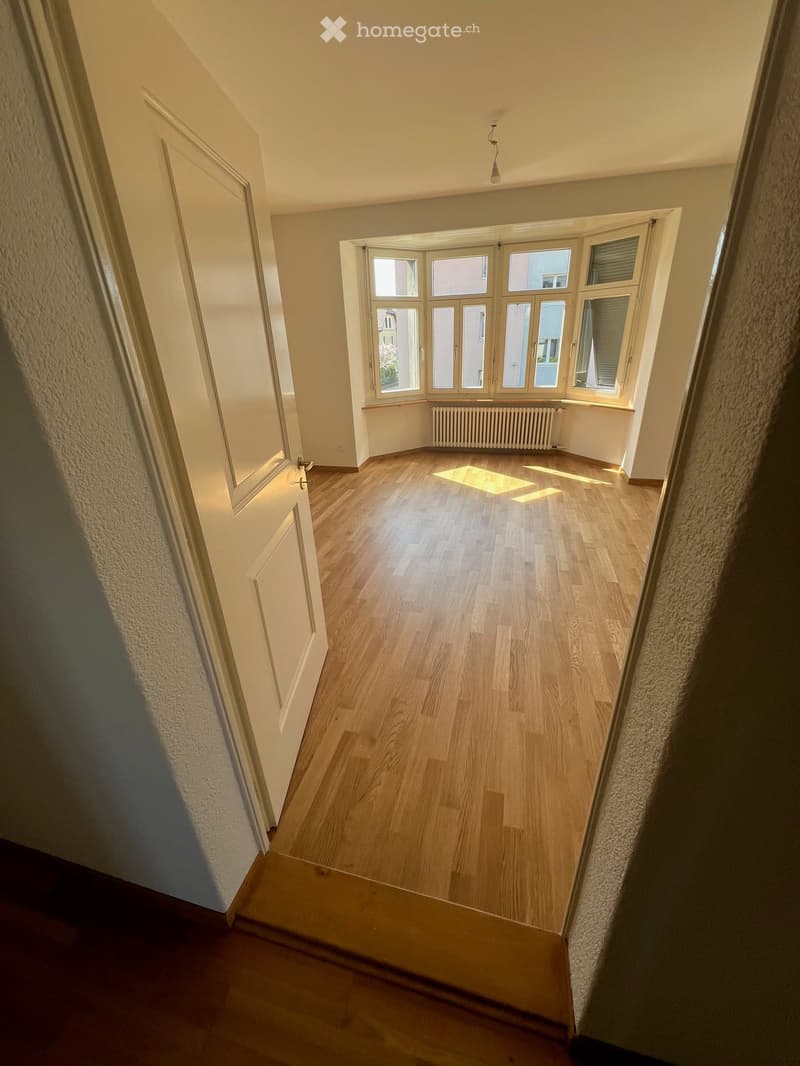 empty room, wooden floor, white walls, large windows, white door, radiator