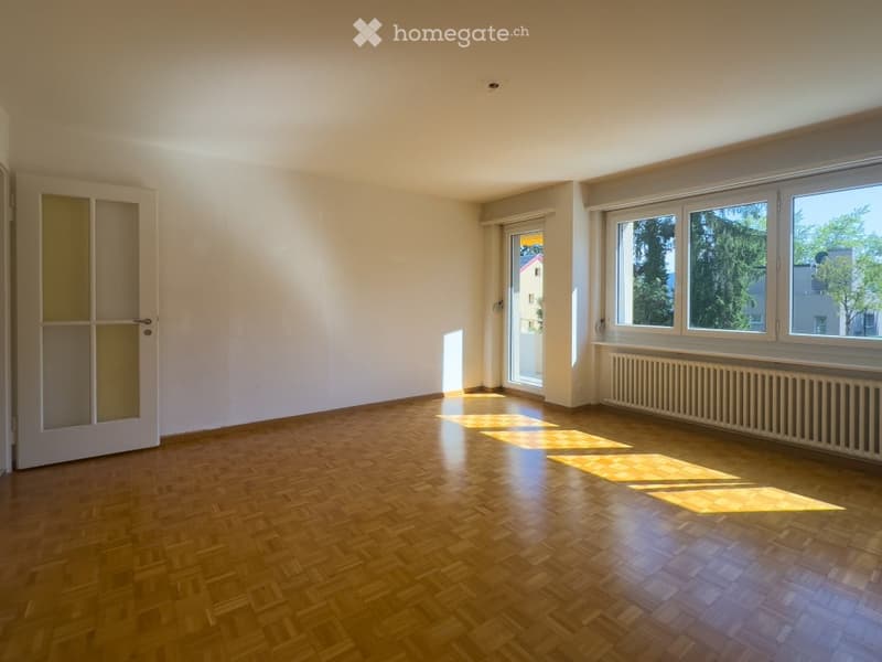 Empty room with wooden flooring, white walls, large windows, and a door leading to a balcony.