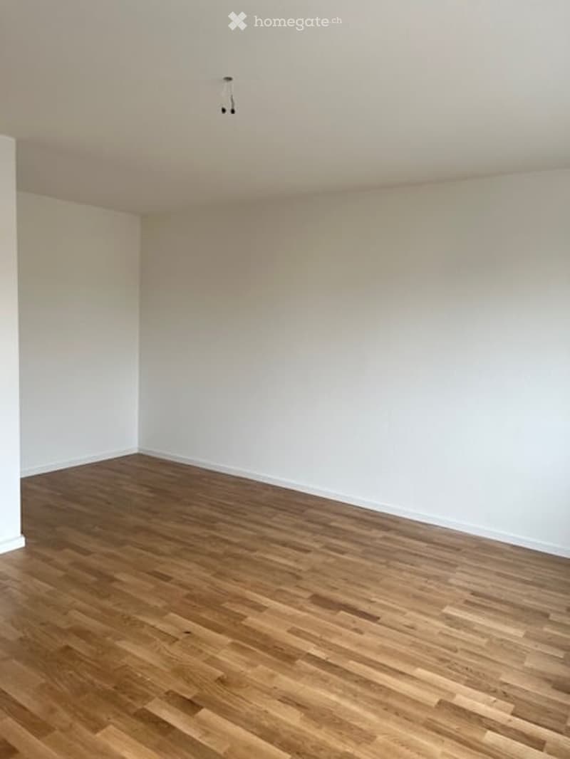 Completely empty room with bare white walls and wooden floor. No furniture or equipment.