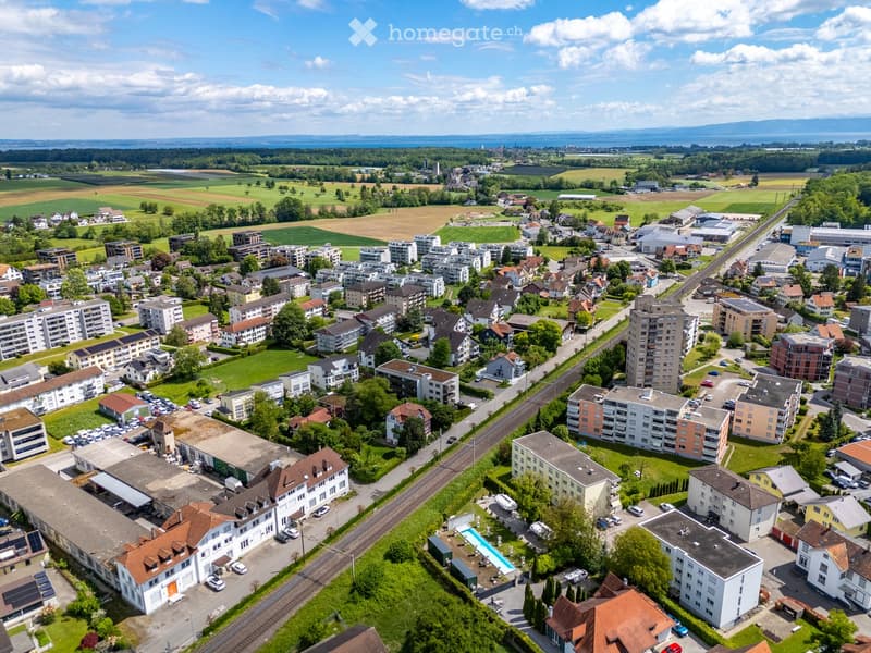 Aerial view of a suburban neighborhood with residential buildings, roads, and a swimming pool in the foreground.