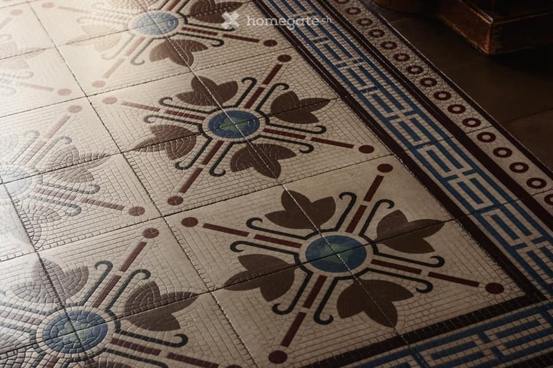 Ornate mosaic tile floor with floral and geometric patterns in shades of beige, brown, and blue.
