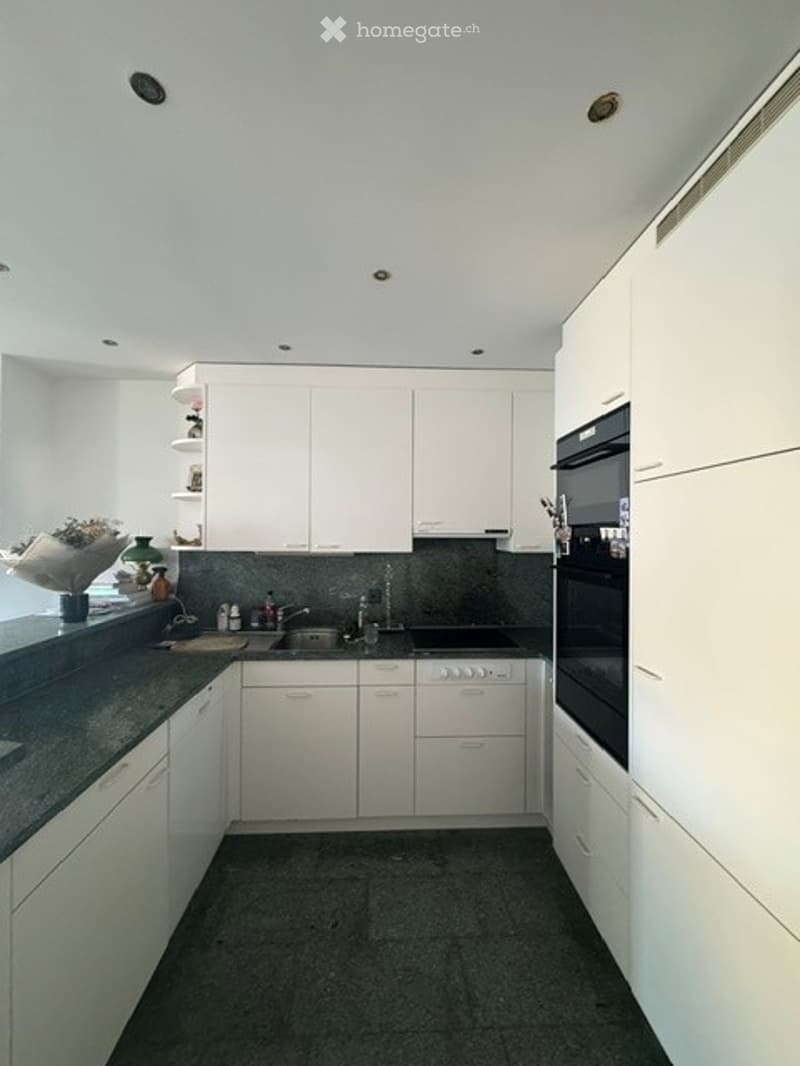 Modern kitchen with white cabinets, dark countertops, and stainless steel appliances including a stove, oven, and sink.