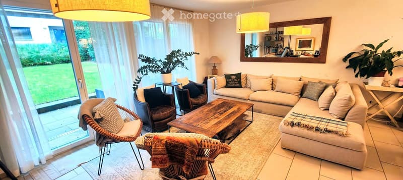 Bright living room with large windows, a beige sectional sofa, wooden coffee table, wicker chairs, and decorative pillows.