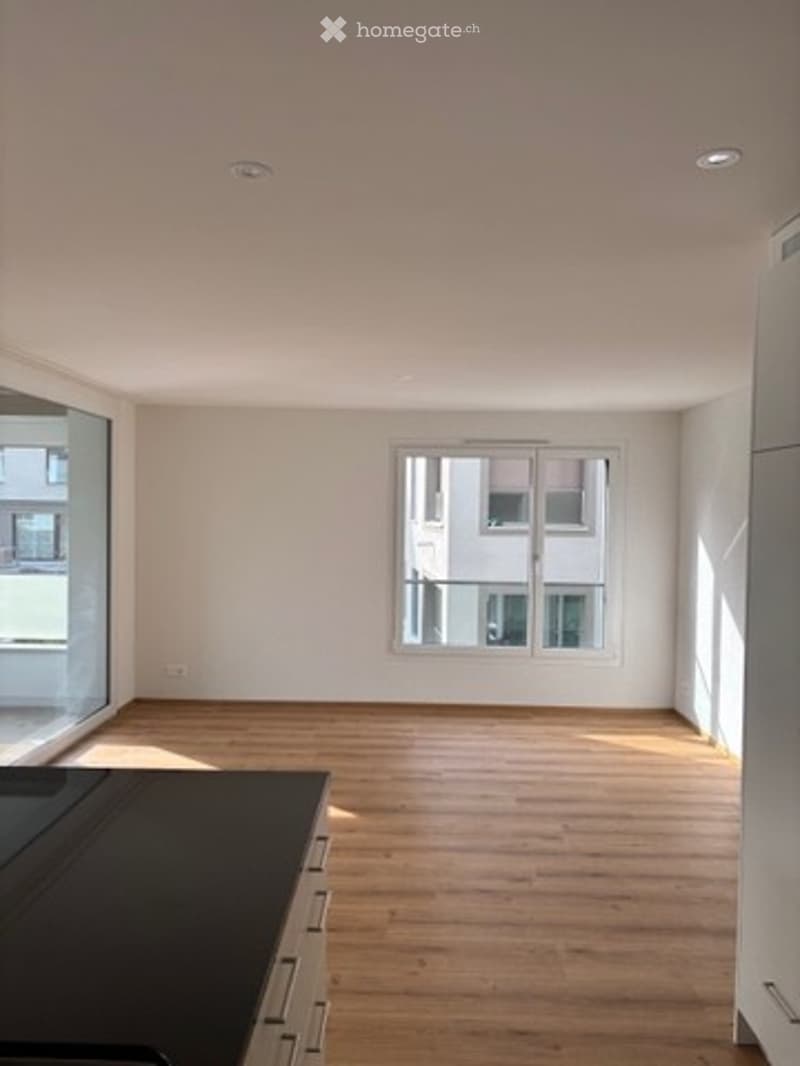Empty room with wooden flooring, white walls, and large windows. No furniture or equipment present.
