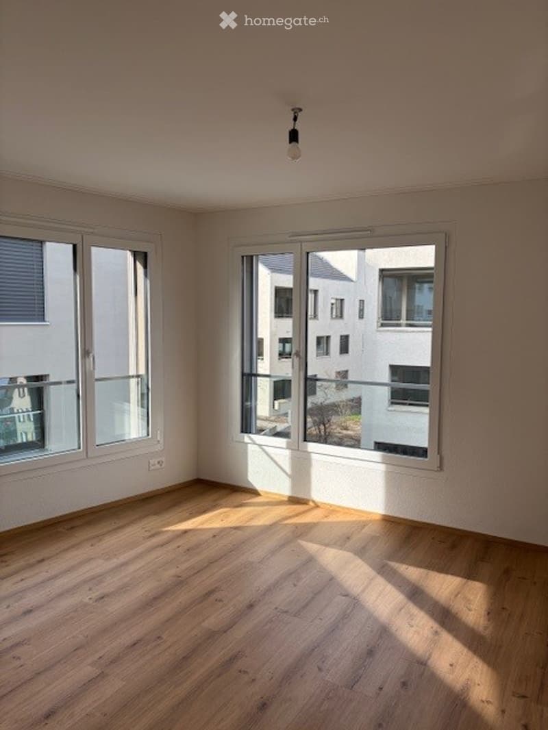 Empty room with wooden flooring, large windows, and natural light. No furniture or equipment present.