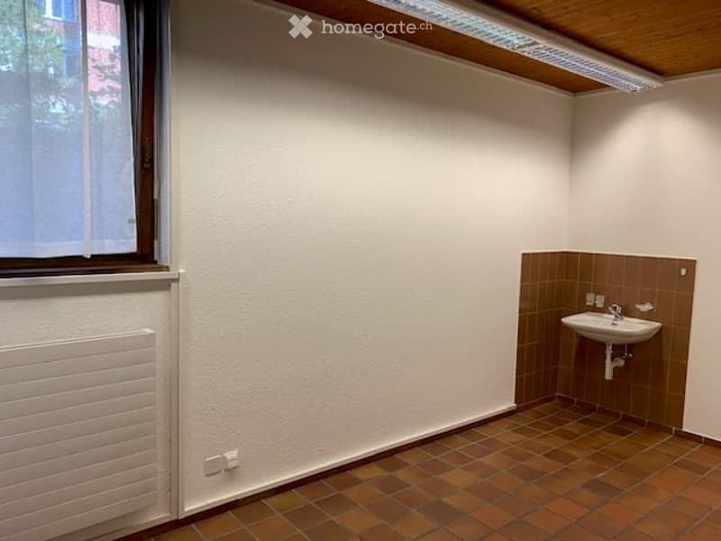 Small bathroom with a single sink, tiled floor, and a window providing natural light.