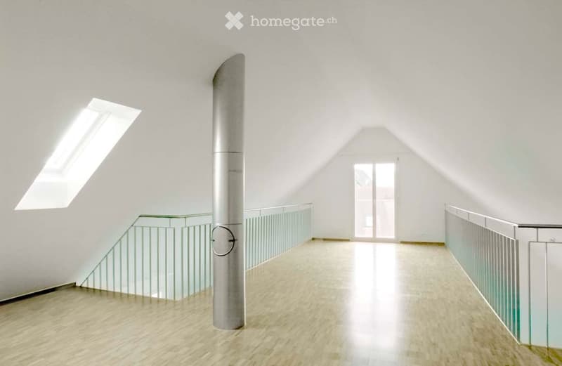 Bright, minimalist hallway with wooden flooring, glass railings, and a central metallic column. Skylight and large window provide natural light.