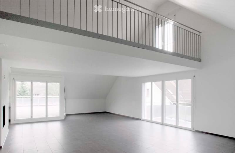 Empty room with white walls, tiled floor, large windows, and a balcony overlooking the space.