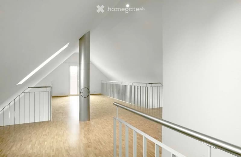 Bright, minimalist hallway with wooden flooring, white walls, and modern metal railings leading to an open space.
