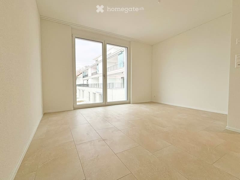 Empty room with beige tiled flooring and large sliding glass doors leading to a balcony area.