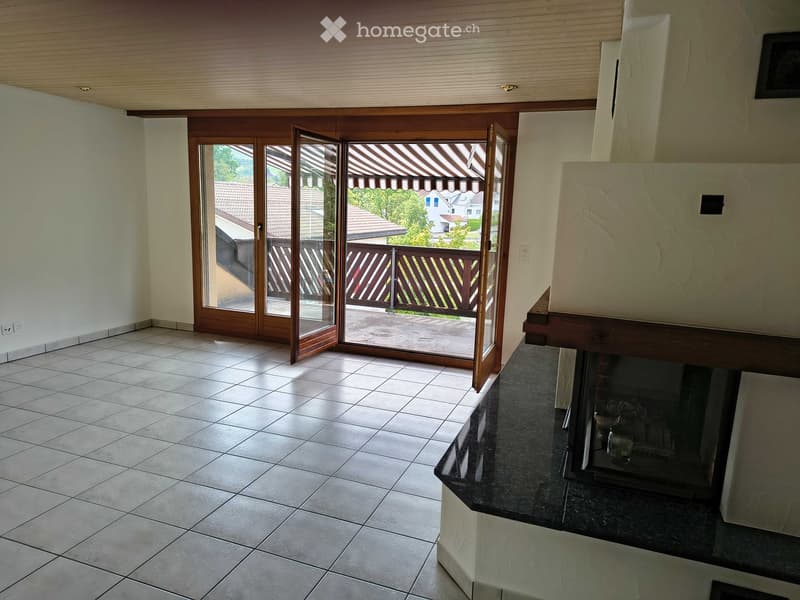 Empty room with tiled floor, large sliding glass doors leading to a balcony, and a fireplace with a wooden mantle.