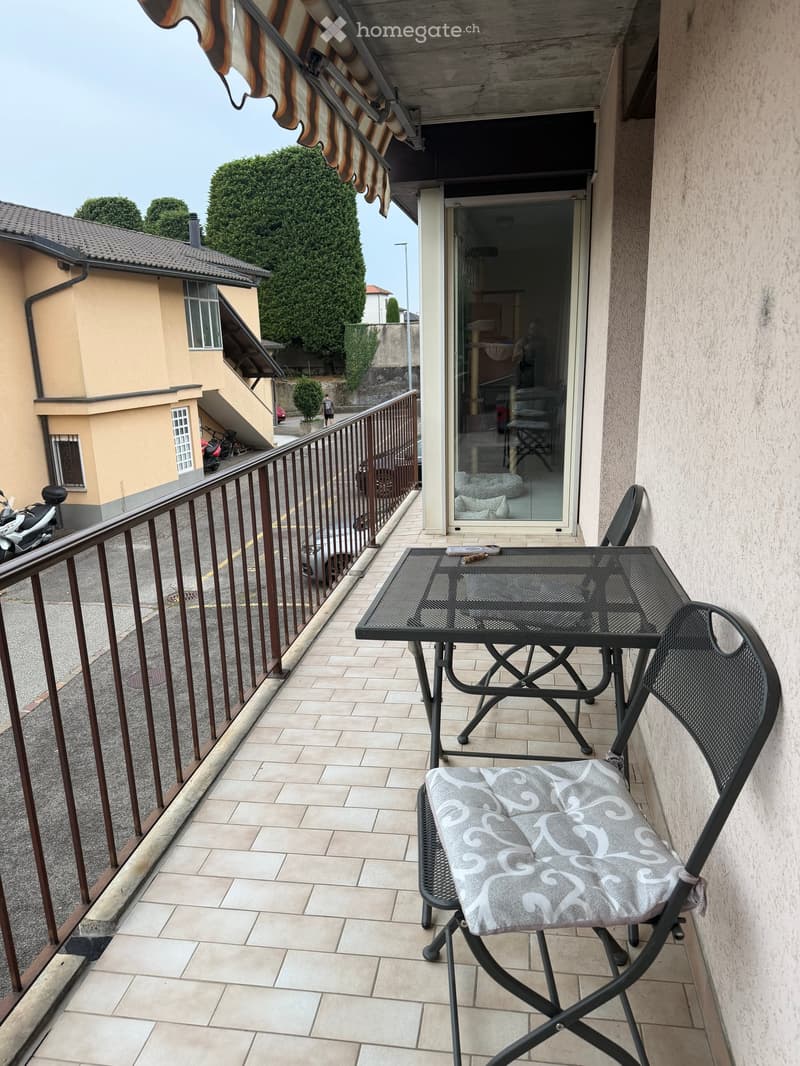 Balcony with tiled floor, metal table, and folding chair with cushion.