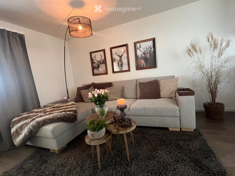 Modern living room with a grey sectional sofa, wooden coffee table, floor lamp, decorative pillows, and artwork on the wall.