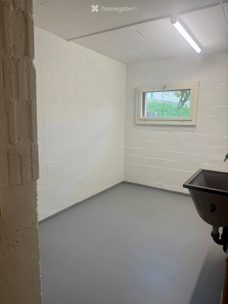 Empty room with white brick walls, a small window, and a sink fixture in the corner.