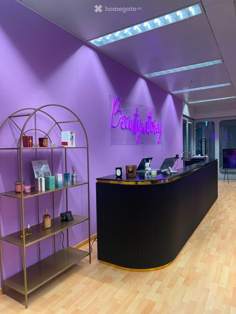 A modern reception area with a curved black counter, a golden shelf holding various products, and a neon sign reading "BeautywithJenna".