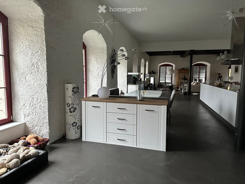 Modern interior with a mix of rustic and contemporary elements, featuring a sofa, a table with a lamp, a cabinet, and a decorative ball on the table.